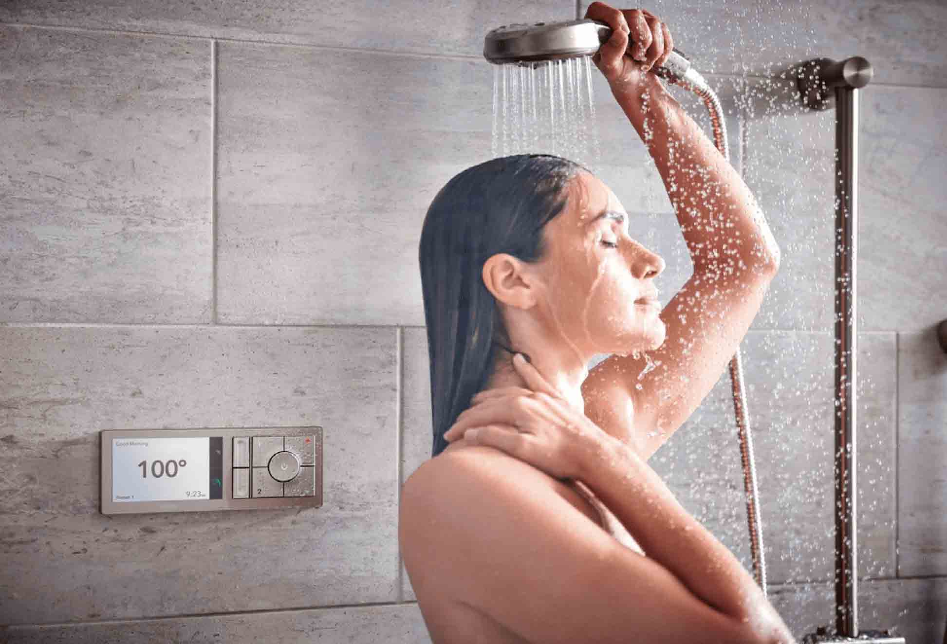 Mujer disfrutando de una ducha caliente, relajándose mientras el agua cae sobre su cabello y piel.