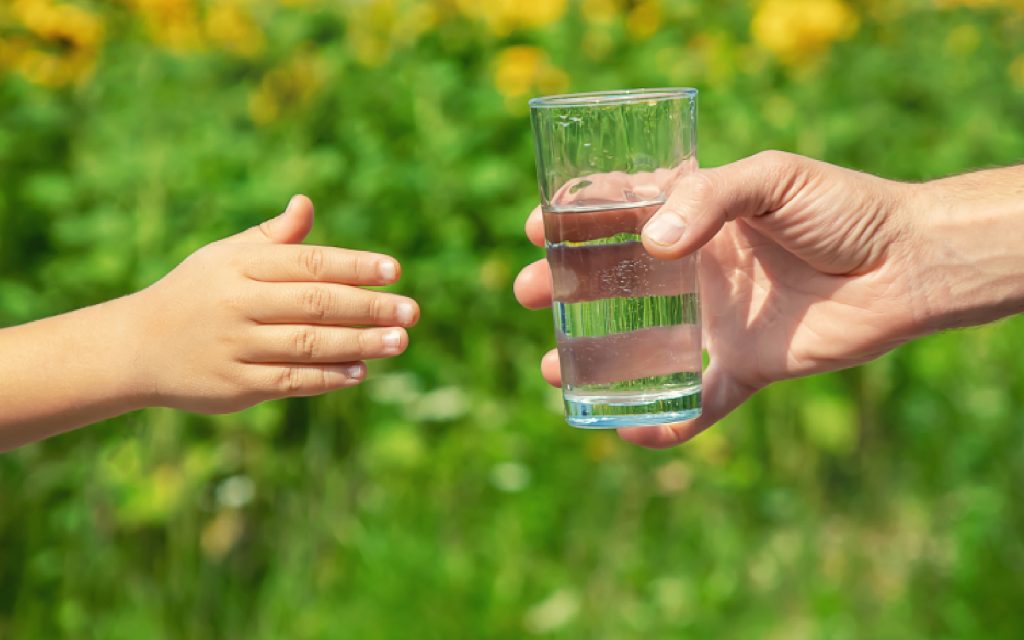Papa dando vaso de agua Kangen a su hijo.